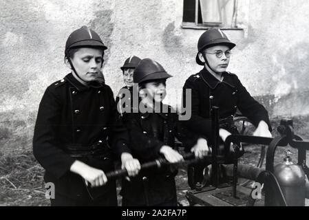 Jungen von der Kinderfeuerwehr betätigen bei einem Übungseinsatz die Wasserpumpe, Deutschland 1930er Jahre. Boys of the junior firefighters using the hand pump during a training, Germany 1930s. Stock Photo