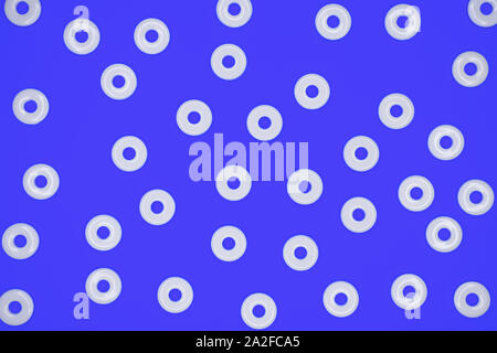 Flat round white plastic beads in irregular pattern on blue cardboard background Stock Photo