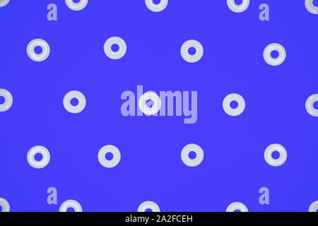 Flat round white plastic beads in regular pattern on blue cardboard background Stock Photo