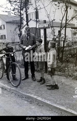 Der Zeppelinheimer Bürgermeister und Luftschiffkapitän Hans von Schiller zieht das Spielzeugauto von drei Jungen auf der Straße auf, bei Frankfurt am Main, Deutschland 1930er Jahre. The mayor of Zeppelinheim and airship captain Hans von Schiller winding up the toy car of three boys on the street, near Frankfurt am Main, Germany 1930er. Stock Photo