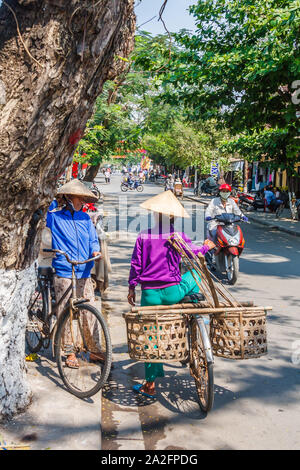 Hoi An, Vietnam - March 3rd 2010: Women on bicycles talking. Cycling is still a popular form of transport. Stock Photo