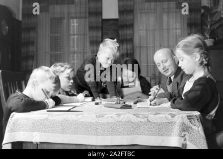 Mitglieder einer kinderreichen Familie bei den Hausaufgaben, Deutsches Reich 1930er Jahre. Members of a extended family doing the homework, Germany 1930s. Stock Photo