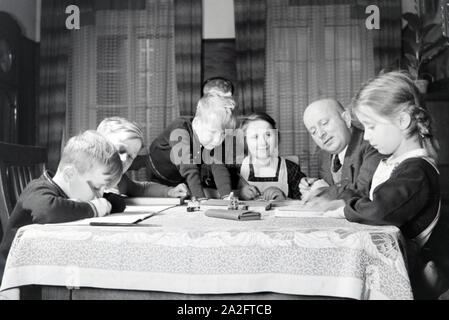 Mitglieder einer kinderreichen Familie bei den Hausaufgaben, Deutsches Reich 1930er Jahre. Members of a extended family doing the homework, Germany 1930s. Stock Photo