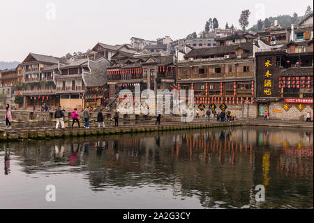 Hunan, China, 14 Nov 2011: Tourists crossing stone bridge at Phoenix Ancient Town. Stock Photo