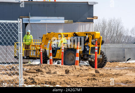Grand Rapids Michigan, March 8, 2019; a construction crew stands on a lift while another worker prepares to rise him up Stock Photo