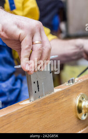 Carpenter establishes the in the old a wooden door mortise lock. Stock Photo