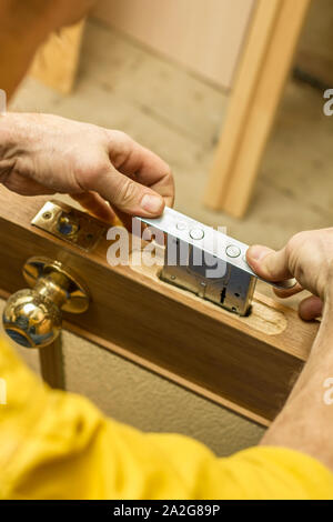Carpenter establishes the in the old a wooden door mortise lock. Stock Photo