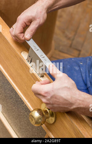 Carpenter establishes the in the old a wooden door mortise lock. Stock Photo