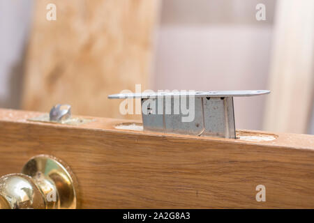 Mortise lock is inserted halfway into the old a wooden door. Stock Photo