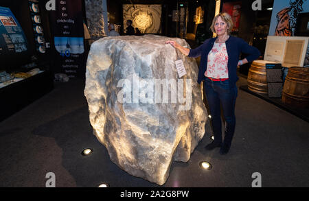 30 September 2019, Lower Saxony, Lüneburg: Hilke Lamschus, historian and director of the German Salt Museum in Lüneburg, stands next to an approximately six-ton stone made of salt that comes from a mine near Helmstedt. Salt secured Lüneburg's prosperity and power for centuries. (to dpa 'Lüneburg and the salt') Photo: Philipp Schulze/dpa Stock Photo