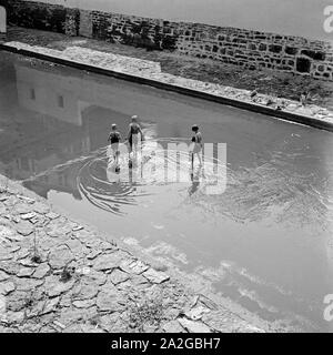 Kinder spielen in einer überschwemmten Straße in Wuppertal, Deutschland 1930er Jahre. Children playing in a flooded street at Wuppertal, Germany 1930s. Stock Photo