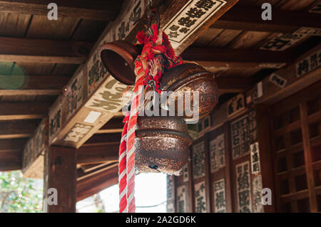 DEC 4, 2018 Aizu Wakamatsu, JAPAN - Old rusty antique Japanese bronze shinto bell or Suzu with rope hanging from wooden ceiling in Shrine at Tsuruga J Stock Photo