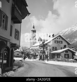 Blick in einen Ortskern mit Kirche und Ladenlokalen, Deutschland 1930er Jahre. view to a twon centre with belfry and a drugstore, Germany 1930s. Stock Photo