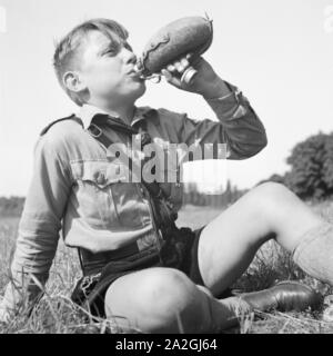 Ein Hitlerjunge nimmt einen Schluck aus seiner Feldflasche, Deutschland 1930er Jahre. A Hitler youth drinking from his waterbottle, Germany 1930s. Stock Photo