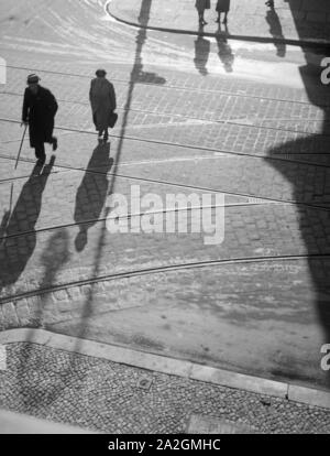 Die Menschen in Berlin werfen lange Schatten, Deutschland 1930er Jahre. people at a street in Berlin with their shadows, Germany 1930s. Stock Photo