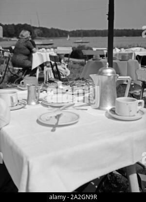 Gedeckte Kaffeetafel in der Außengastronomie, Deutschland 1930er Jahre. Perfect table for coffee in the afternoon, Germany 1930s. Stock Photo