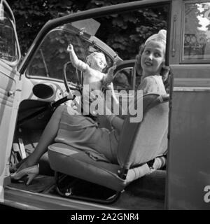 Eine junge Frau mit einer Putte im offenen Wagen, Deutschland 1930er Jahre. A young woman playing with a putto in an open car, Germany 1930s. Stock Photo