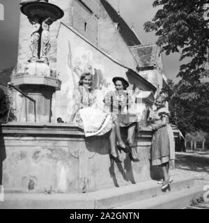 Drei junge Frauen an einem Brunnen in der Wachau in Österreich, Deutschland 1930er Jahre. Three young women in front of a fountain at the Wachau area in Austria, Germany 1930s. Stock Photo