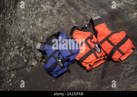Two life jackets and a radio are on the rocky coast, on a sunny spring day. Stock Photo