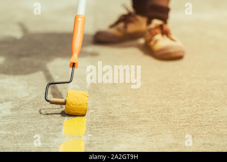 Male students use small paint rollers to paint yellow lines on the cement floor for Sepak Takraw training. Stock Photo