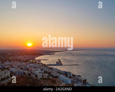 The sun rises over the seaside town. Aerial view of town, sea and harbor.