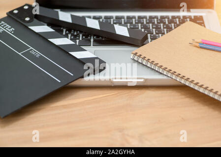 Video Editing,Movie clapper laptop and pencil notepad on the wood table top view shot.dark effect Stock Photo