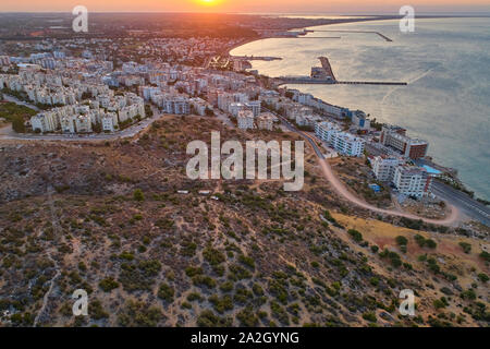 The sun rises over the seaside town. Aerial view of town, sea and harbor.
