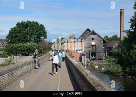 Tourists Cross Tramway Bridge over River Avon & Cox's Yard Restaurant, Bar & Pub or Public House on Banks of River Avon Stratford-upon-Avon Stock Photo