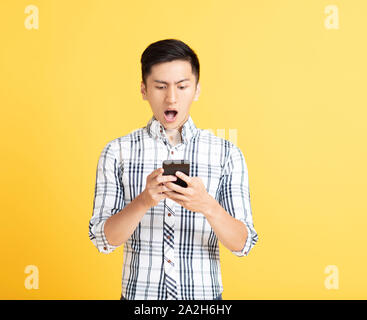 surprised young man using smart phone Stock Photo