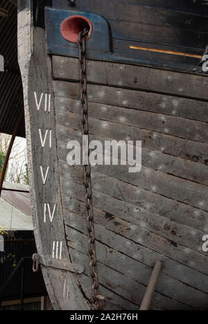 Bow of wooden boat with anchor chain and depth markings Stock Photo