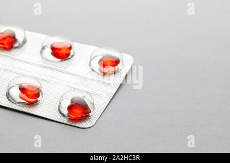 Love pills. Blister pack with red heart shaped pills. Tablets for lovers or potency. Gray background. Copy space for text Stock Photo