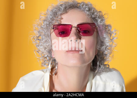 Mature grey-haired pretty woman wearing pink glasses Stock Photo
