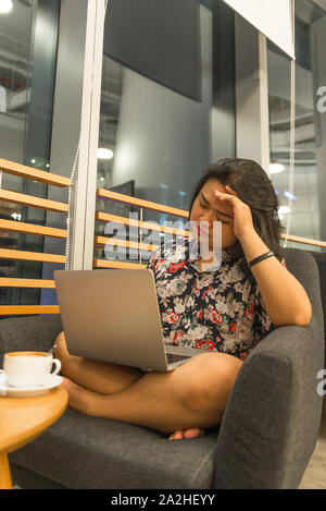 Frustrated female freelancer working on laptop at coffee table Stock Photo