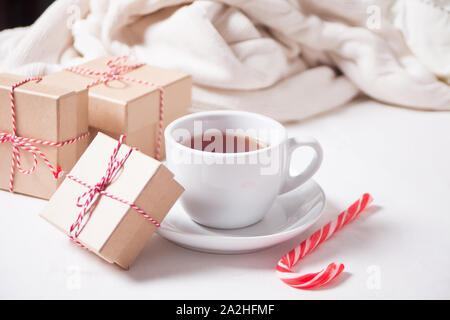 Cup of tea, candy cane, Christmas gift boxes, knitted plaid on the white background. Stock Photo