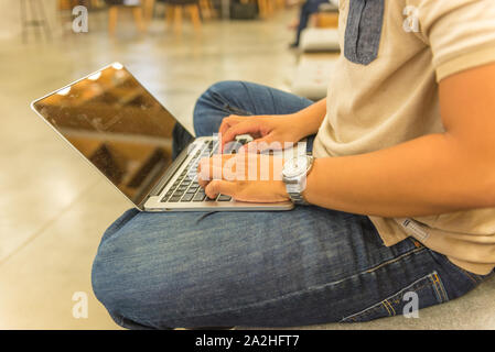 Sideview of human hand wearing watch and typing laptop keyboard Stock Photo