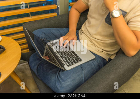 Human comfortably sitting on armchair and using laptop at home Stock Photo