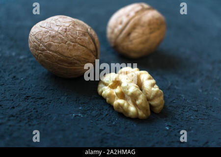Unshelled walnuts and peeled close-up on a black background. Stock Photo