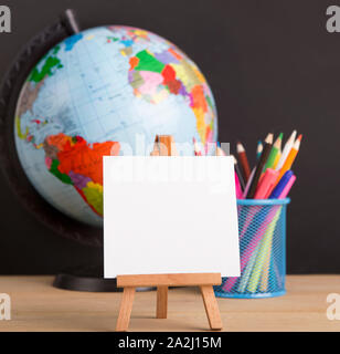 Close up of white blank easel for writing text, world globe Stock Photo