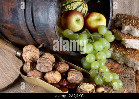Autumn table filled with nuts, traditional bread, apples, grapes and gourds Stock Photo