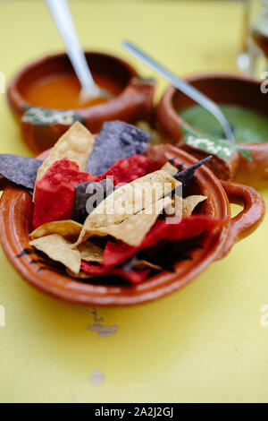 Mexican nachos on a yellow table. Green and red sauces on the background. Stock Photo
