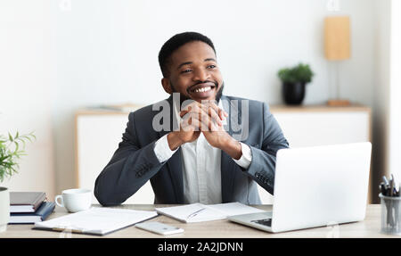 Pensive african businessman dreaming about something while working in office Stock Photo