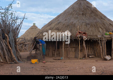 Turmi, Ethiopia - Nov 2018: Hamer tribe woman sweeping the yard in front of the house, Omo valley Stock Photo