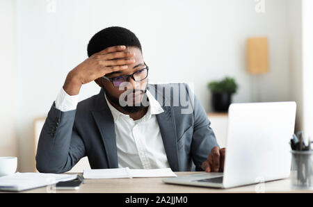 Tired businessman working on laptop in office Stock Photo