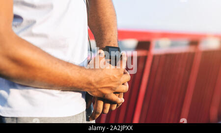 Hands of afro guy checking heart rate on smartwatch Stock Photo
