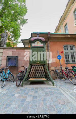 Gamla Stan, Stockholm, Sweden: A old-fashioned, green Rikstelefon telephone kiosk, surrounded by bicycles, stands by a wall on a cobbled pavement. Stock Photo