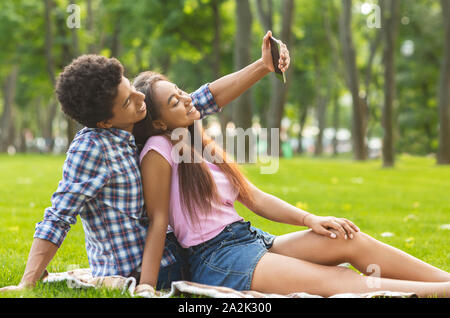 Couple of teenagers taking selfie on picnic outdoors Stock Photo