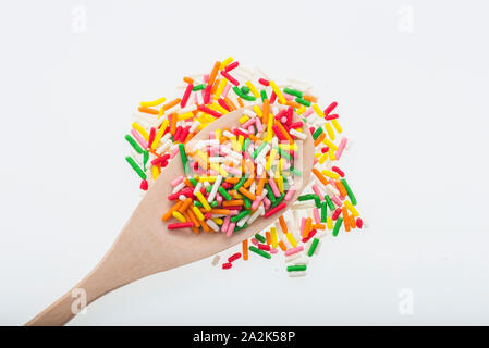 Colorful sugar sprinkles on wooden spoon isolated on white Stock Photo