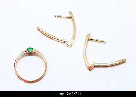 Golden ring with green emerald and pair of earrings on white background. Jewelry gold set top view Stock Photo