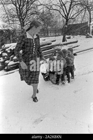 Schlittenfahren an Weihnachten bei einer Familie mit Vierlingen, Deutschland 1930er Jahre. Riding a sleigh at christmas at a family with quadruplet girls, Germany 1930s. Stock Photo