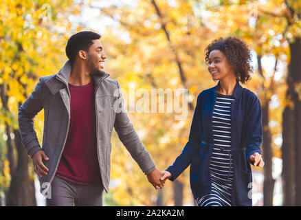 Black couple in holding hands while walking by autumn forest Stock Photo
